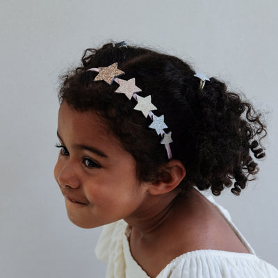 Child wearing a headband with star-shaped details on a plain background