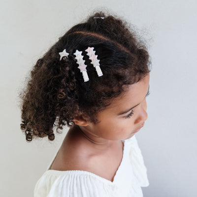 girl wearing layered star hair clips in her hair against a white background