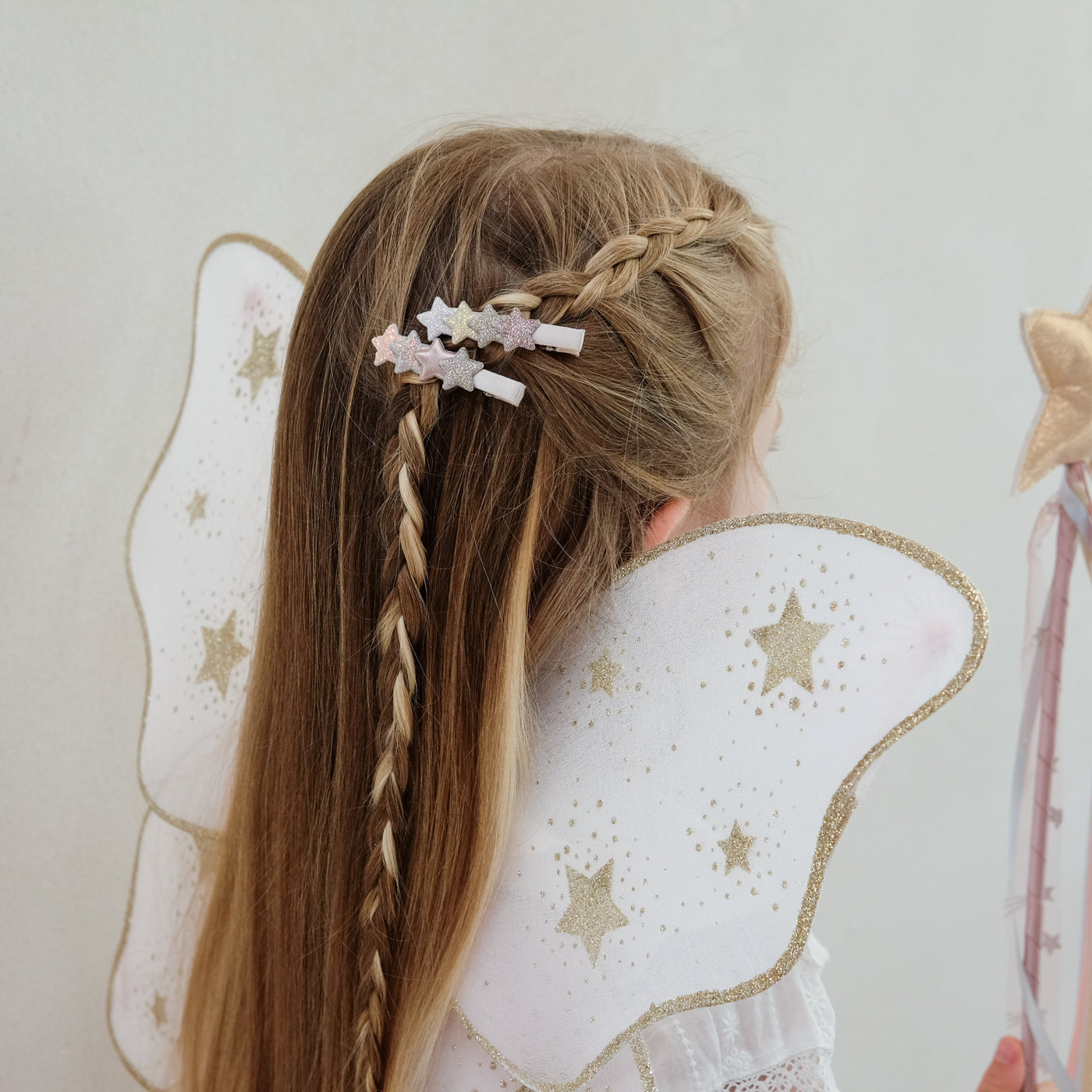 girl wearing layered star hair clips in her hair against a white background