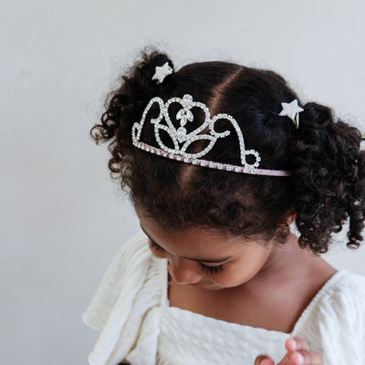 Child wearing a sparkling tiara with a plain background
