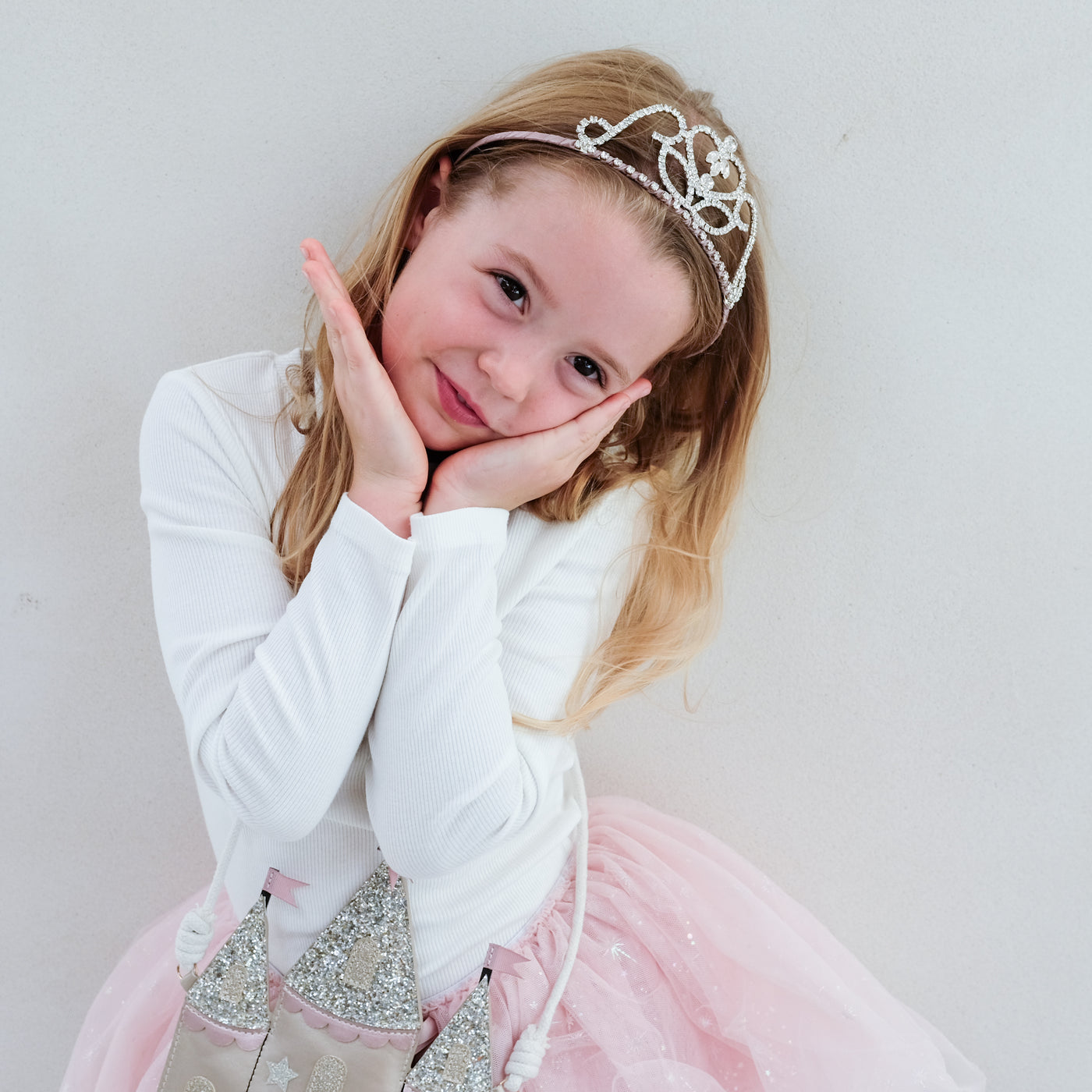 Young girl in a princess costume with a tiara against a plain background