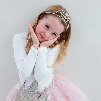 Young girl in a princess costume with a tiara against a plain background