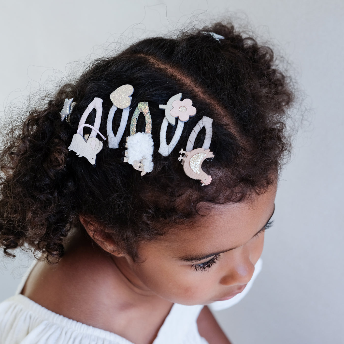 girl wearing farm animal mini clic clacs in her hair against a plain background
