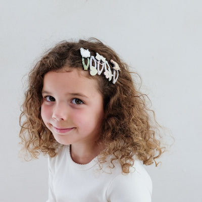 girl wearing farm animal mini clic clacs in her hair against a plain background