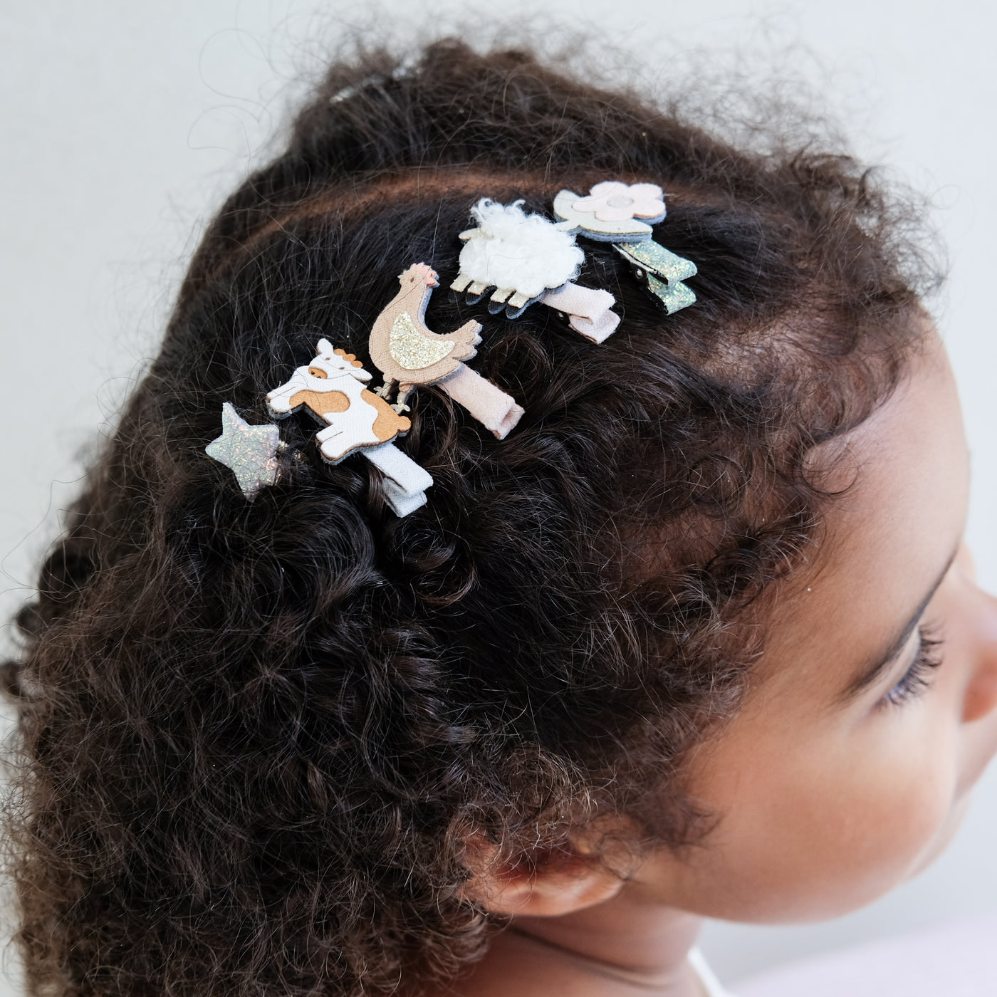 girl wearing farm animal mini clips against a plain white background