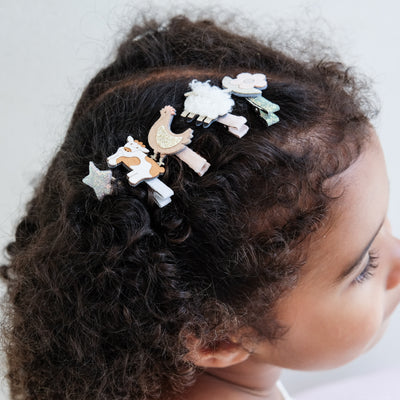 girl wearing farm animal mini clips against a plain white background