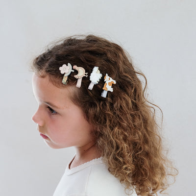girl wearing farm animal mini clips against a plain white background