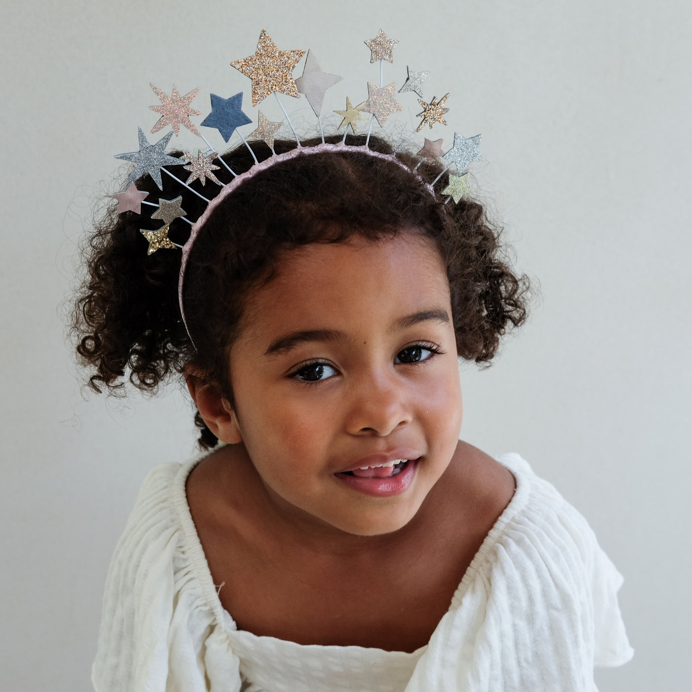 Child wearing a statement star-shaped headband with a plain background