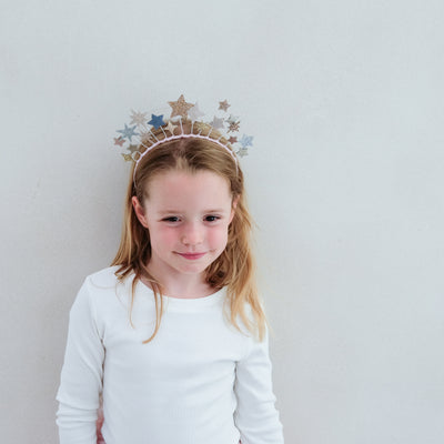 Young girl wearing a decorative star headband against a plain background