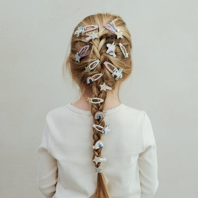 Person with braided hair adorned with various hair clips on a plain background