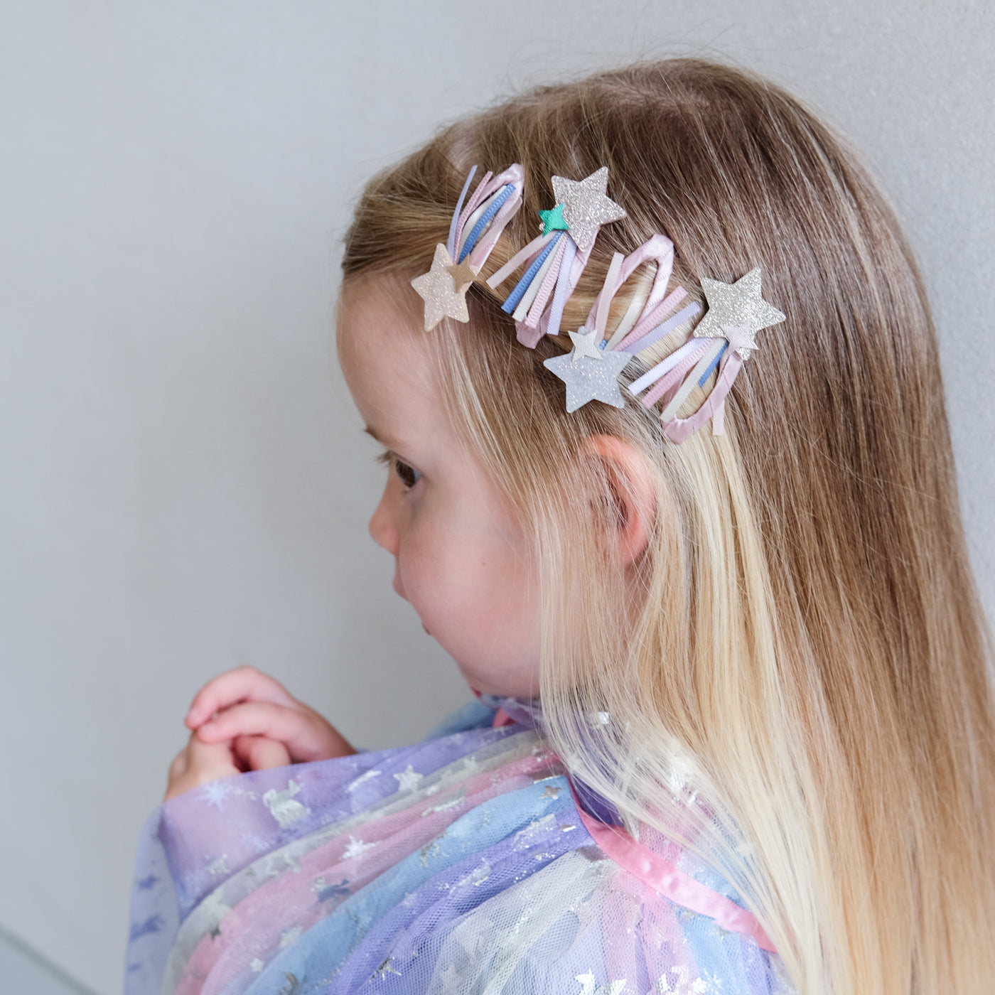 girl wearing shooting star trail hair clips in her hair against a white background
