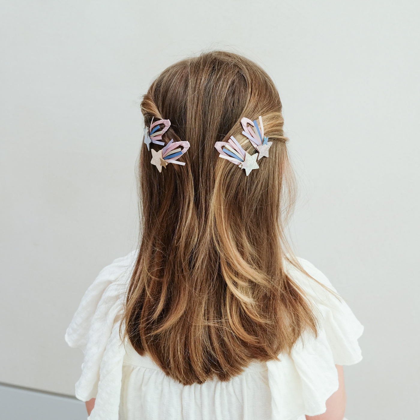 girl wearing shooting star trail hair clips in her hair against a white background