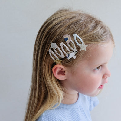 Child with decorative hair clips on a plain background