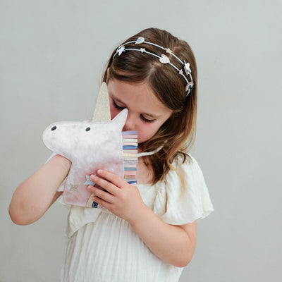 Young girl holding a unicorn bag against a plain background