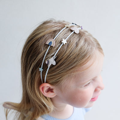 Child wearing unicorn double alice band with a plain background