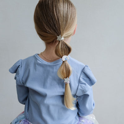 girl wearing rainbow & star ponies in hair against a white background