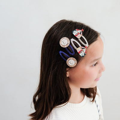 Child with circus themed lion hair clips on a plain background