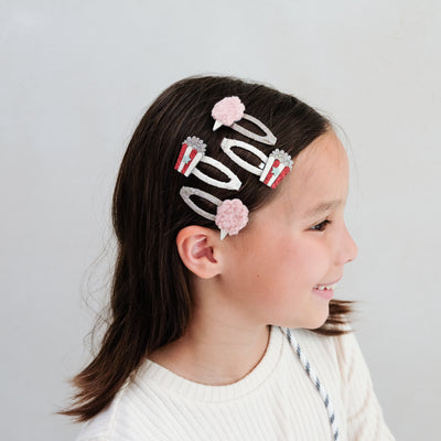 girl wearing popcorn and candy floss hair clips in her hair against a white background