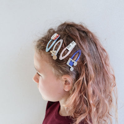 girl wearing music themed clic clac hair clips in her hair against a white background