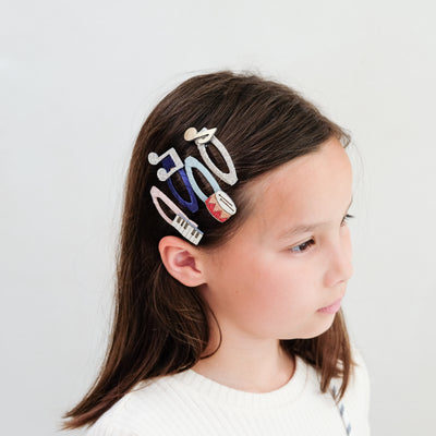 girl wearing music themed clic clac hair clips in her hair against a white background