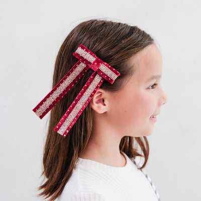 girl wearing red circus bow hair clip in her hair against a white background
