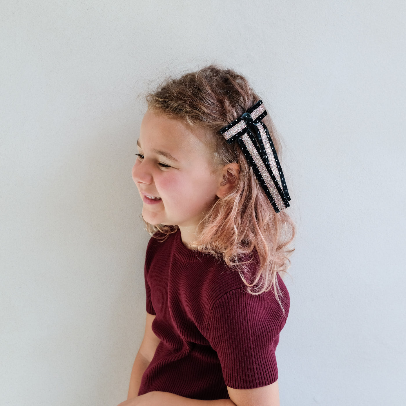 girl wearing green circus bow hair clip in her hair against a white background