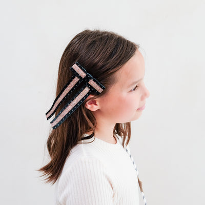 girl wearing green circus bow hair clip in her hair against a white background