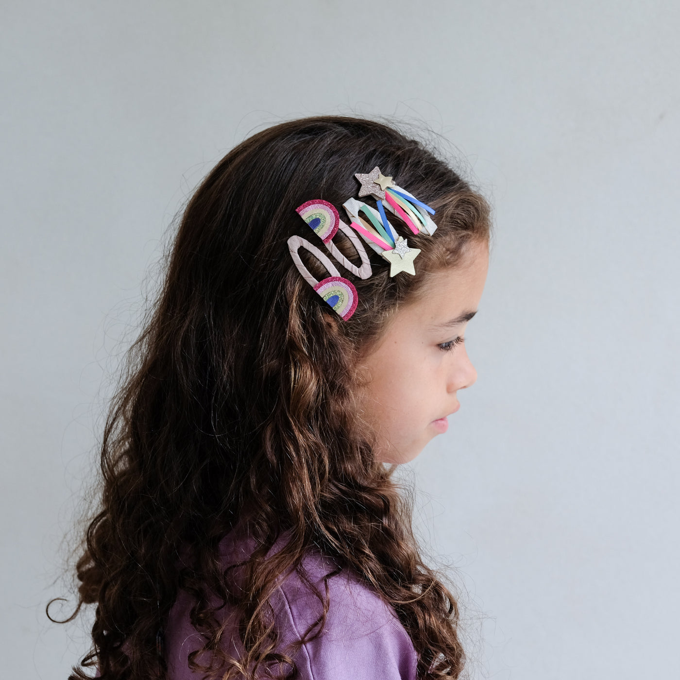 girl wearing disco over the rainbow hair clips in her hair against a white background