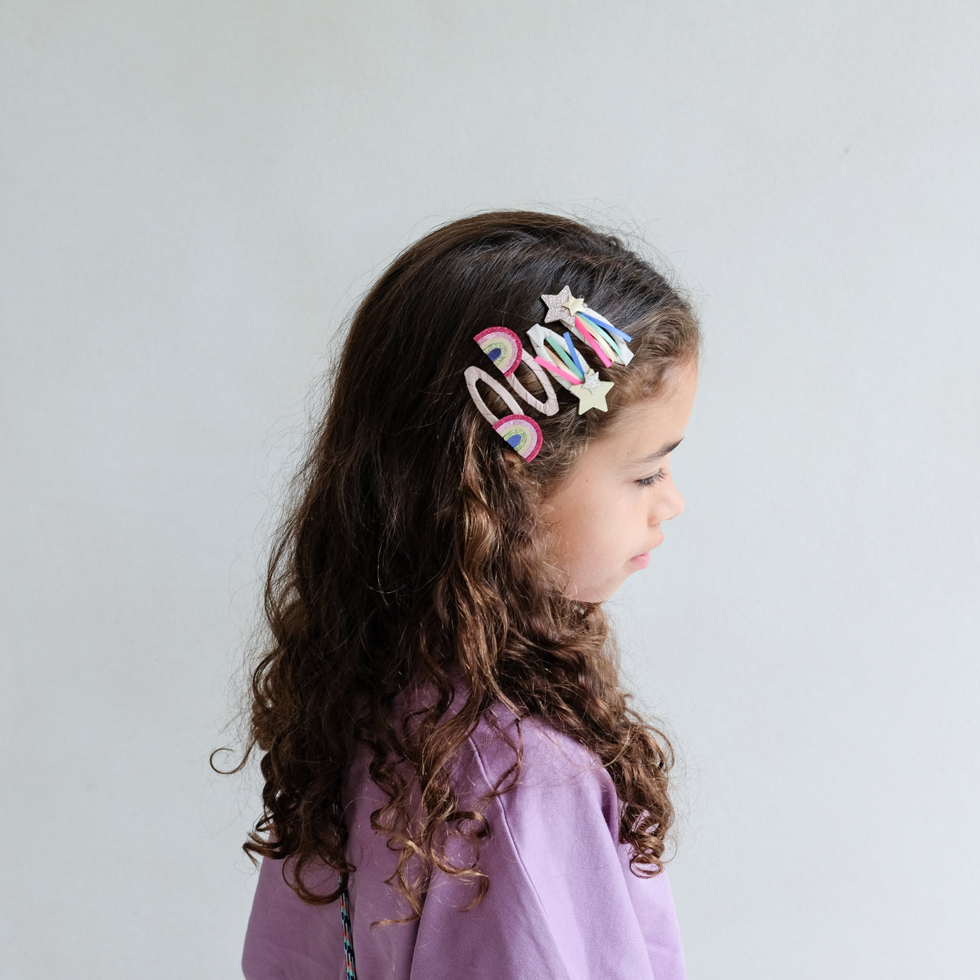 girl wearing disco over the rainbow hair clips in her hair against a white background