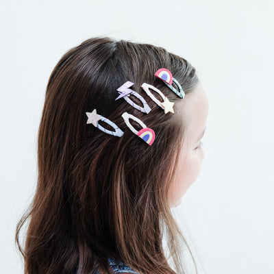 young girl wearing Rainbow mini clic clacs in her hair against a plain background