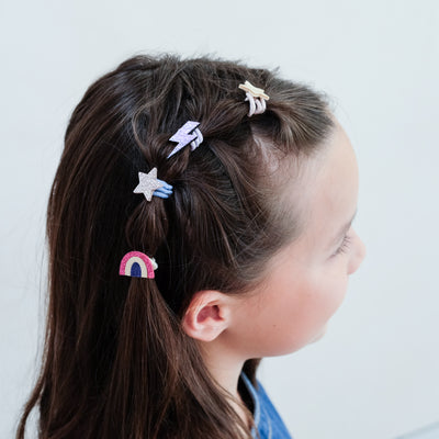 girl wearing rainbow mini ponies in hair against a white background