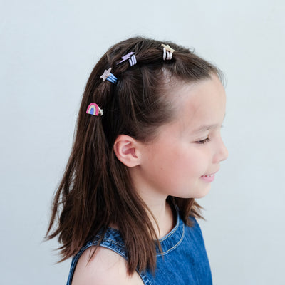 girl wearing rainbow mini ponies in hair against a white background