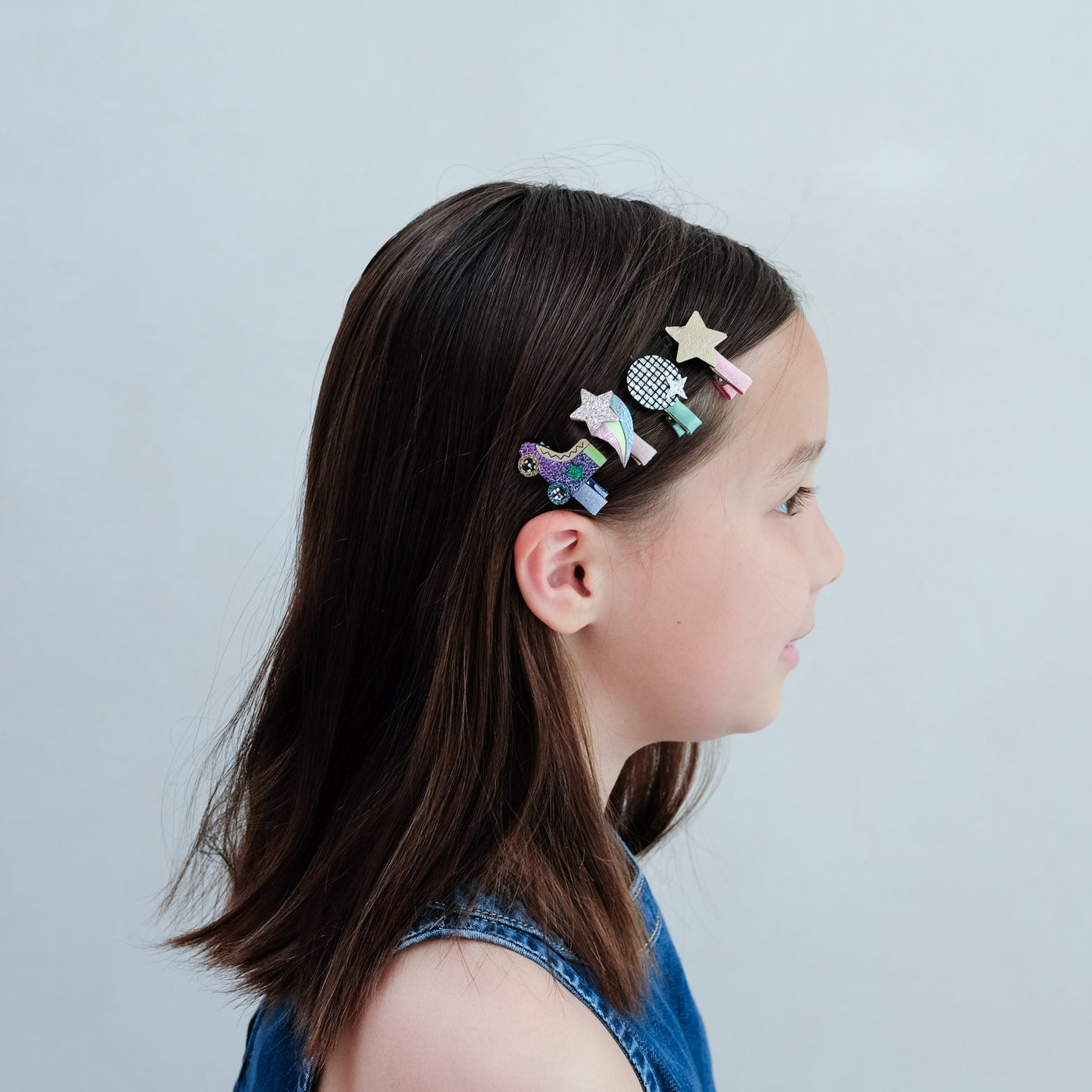Girl with colourful disco diva hair clips in her hair against a plain background