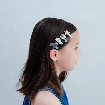 Girl with colourful disco diva hair clips in her hair against a plain background