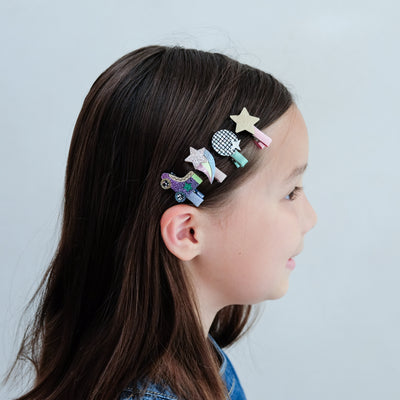 Girl with colourful disco diva hair clips in her hair against a plain background