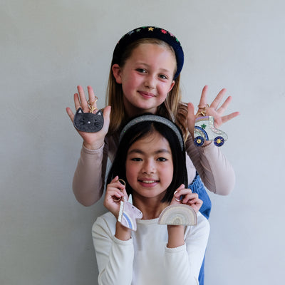 Two children holding keyrings  against a plain background