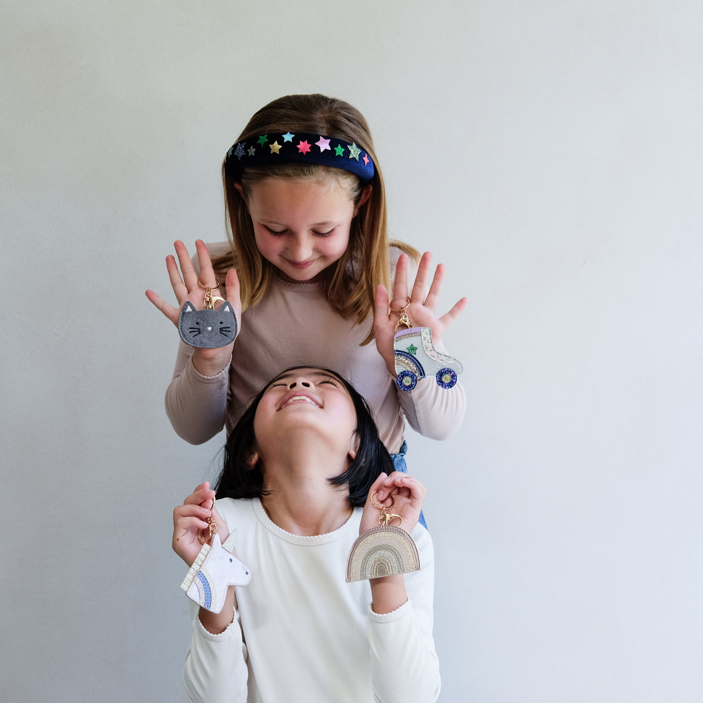 Two children holding colourful keyrings against a plain background