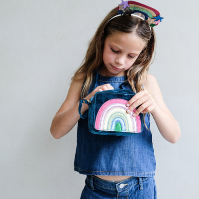 Young girl holding a colourful rainbow bag with a plain background