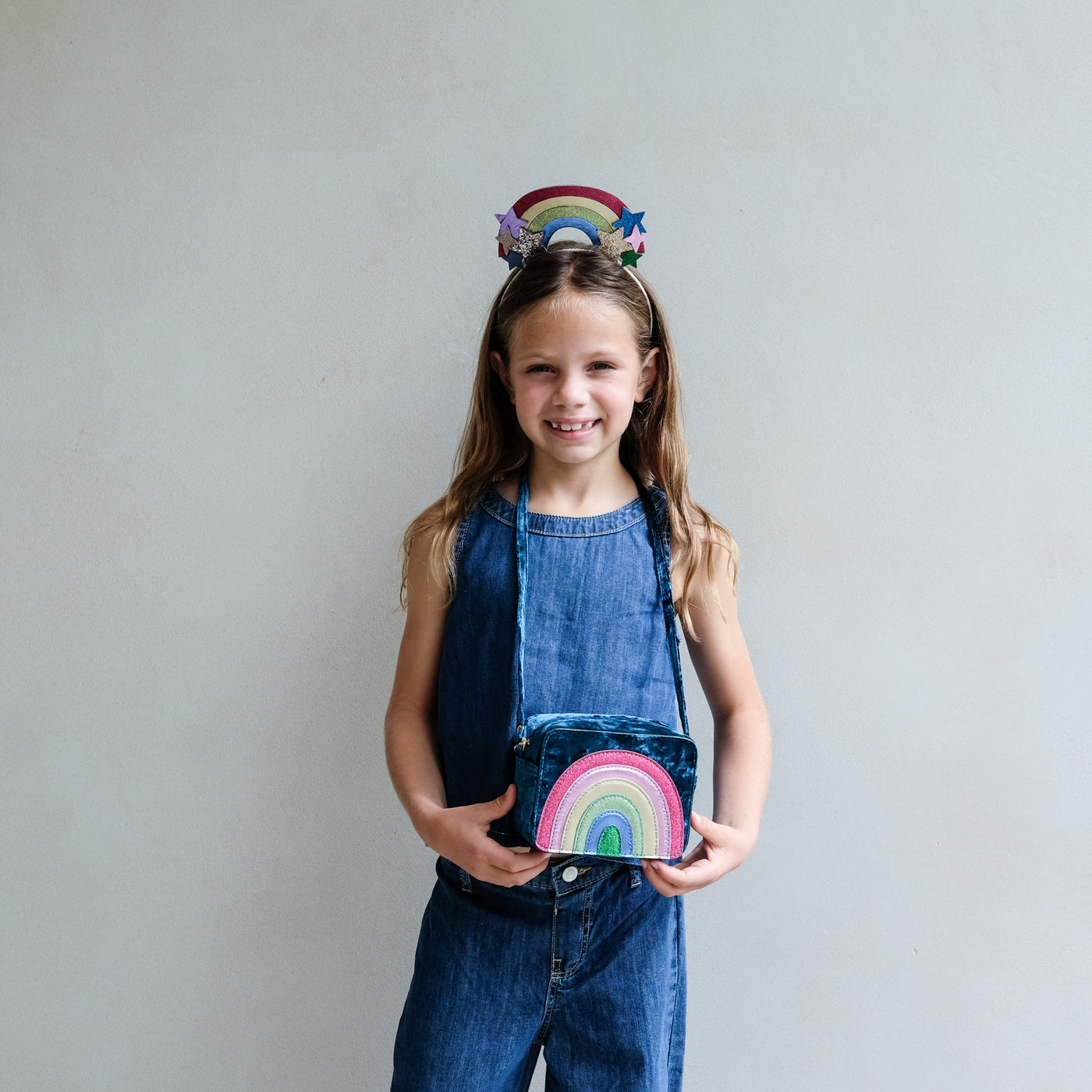 Young girl holding a colourful rainbow bag with a plain background