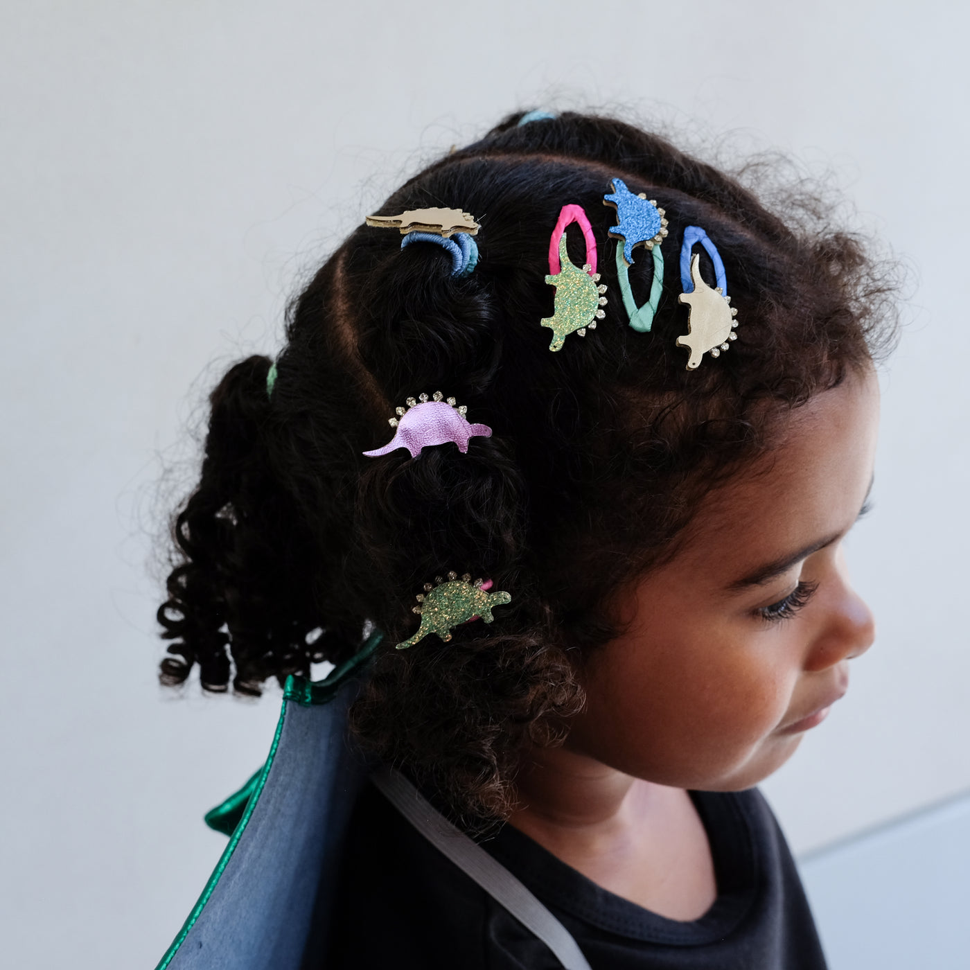 girl wearing dinosaur themed hair accessories against a plain background