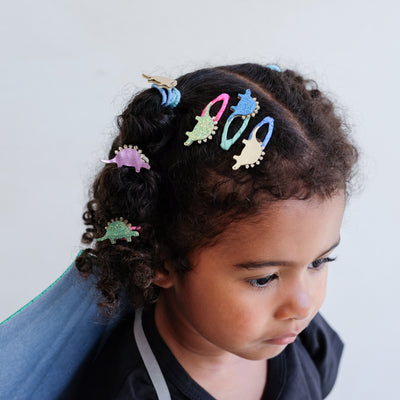 girl wearing dinosaur themed hair accessories against a plain background