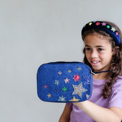 Girl wearing a night sky velvet cross body bag against a plain background