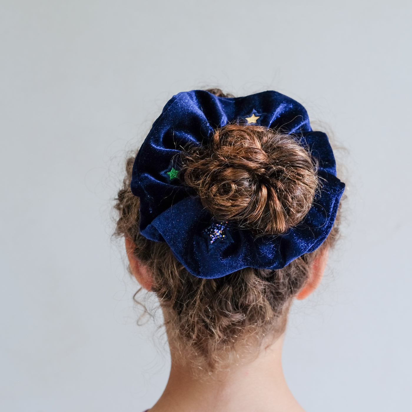 girl wearing constellation velvet scrunchie in hair against a white background