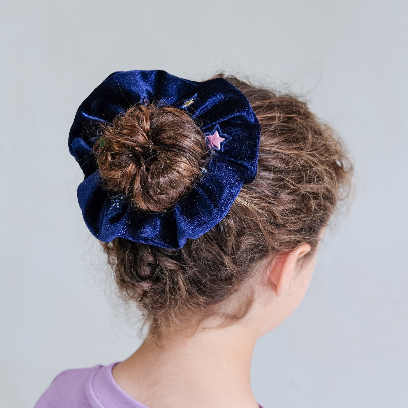 girl wearing constellation velvet scrunchie in hair against a white background