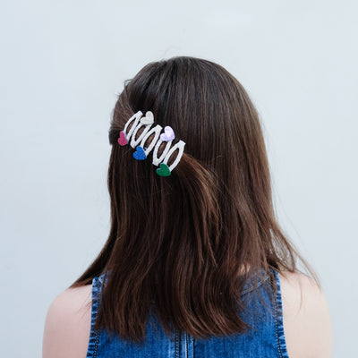 girl wearing jazzy heart mini clic clacs in hair against a plain background
