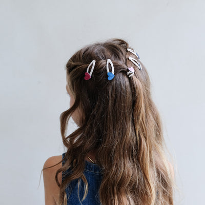 girl wearing jazzy heart mini clic clacs in hair against a plain background