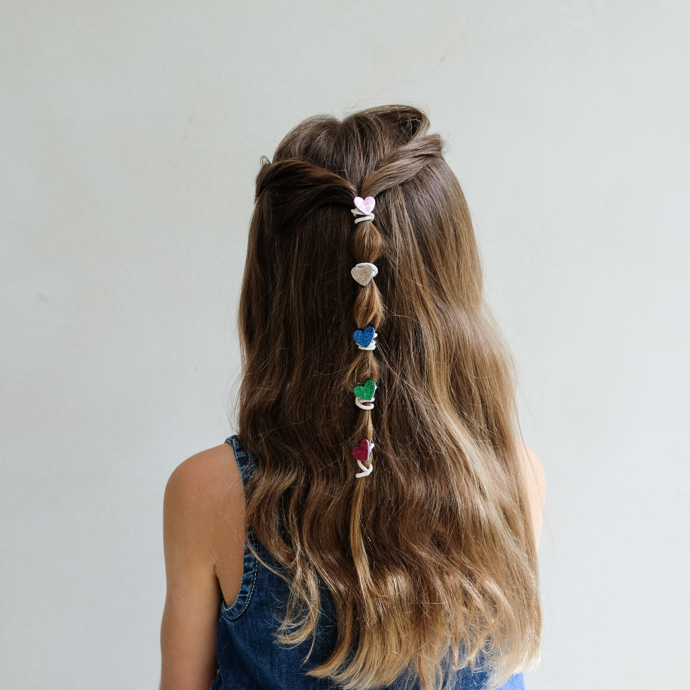 girl wearing mini hearts mini ponies in hair against a white background