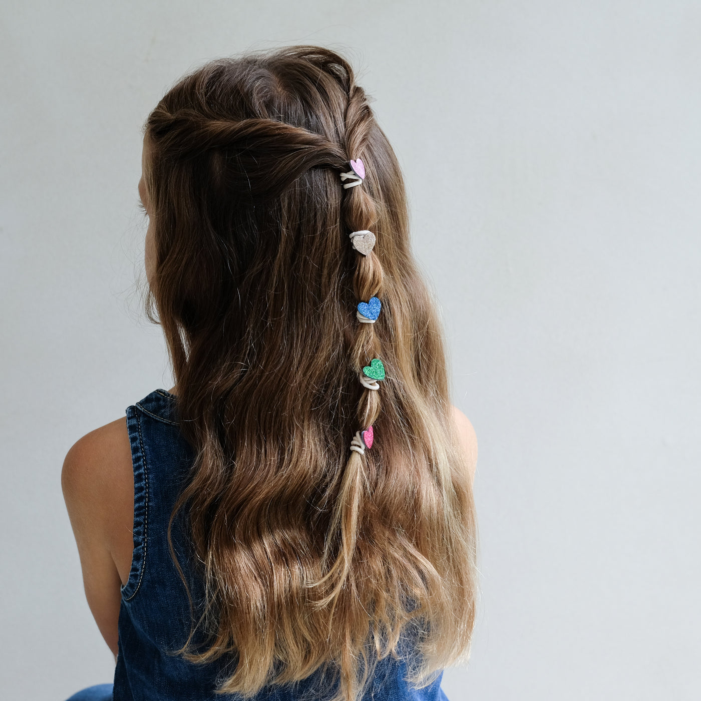 girl wearing mini hearts mini ponies in hair against a white background