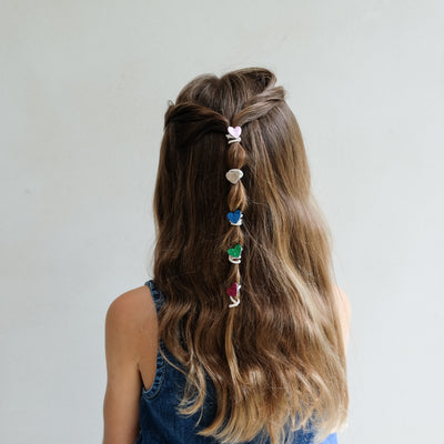 girl wearing mini hearts mini ponies in hair against a white background