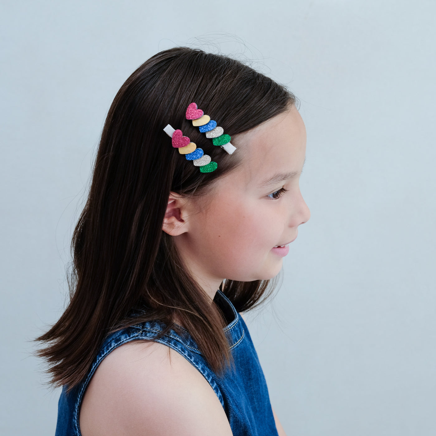 girl wearing jazzy layered heart clips in her hair against a white background